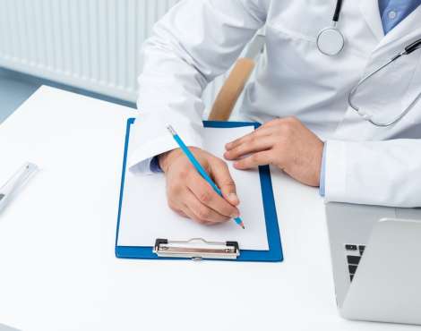 cropped shot of doctor writing in clipboard at workplace